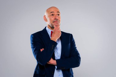 Thinking middle aged man wearing bow tie and blazer while standing at isolated white background. Copy space.