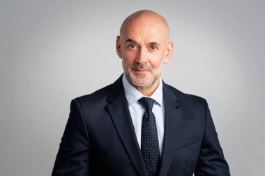 Portrait of caucasian businessman looking at camera.. Confident mature male professional is in suit. He is against gray background.