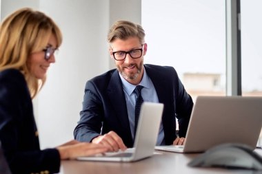 Toplantı odasında dizüstü bilgisayarda çalışan iki iş adamının vurulması. Ofiste takım çalışması. İş kadını ve işadamı mali verileri analiz ediyor. 