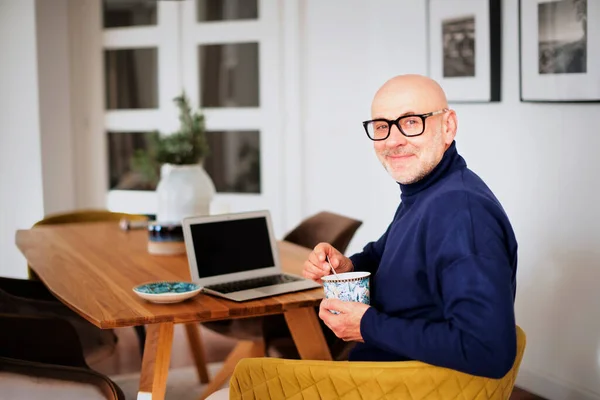 家で椅子でリラックスしてお茶を飲む中年男性の肖像画 幸せな男性身に着けているTurtleeckセーターと眼鏡 — ストック写真