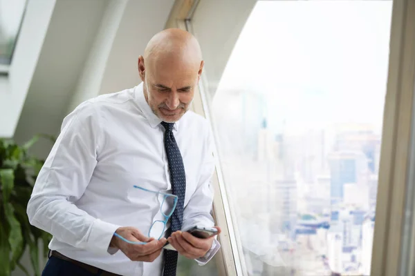 Mid Aged Confident Businessman Standing Window Text Messaging — Stock Photo, Image