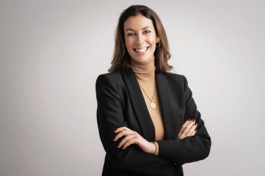 Çekici, orta yaşlı, gülümseyen ve kameraya bakan bir kadının yakın çekimi. Esmer, kadın balıkçı yaka kazak ve siyah ceket giyerken arka planda dikiliyor. Boşluğu kopyala. 