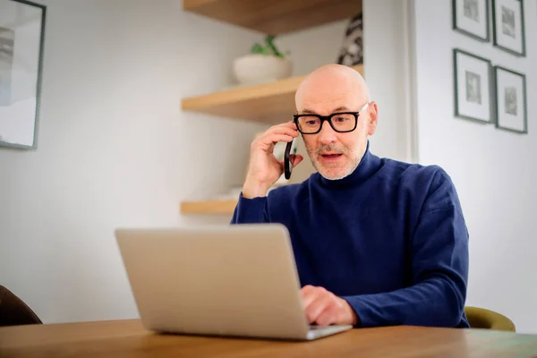 Překvapený Muž Středního Věku Telefonuje Používá Notebook Když Pracuje Domova — Stock fotografie