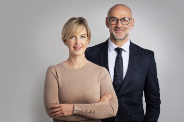 Bir grup iş adamı izole arka planda bir arada duruyorlar. Orta yaşlı iş kadını ve işadamı kameraya bakıyor ve gülümsüyor.. 