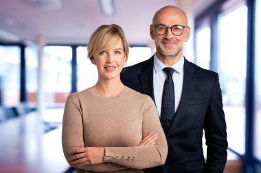 Bir grup iş adamı konferans odasında bir arada duruyorlar. İş kadını ve işadamı kameraya bakıyor ve gülümsüyor.. 