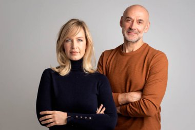 İzole edilmiş beyaz arka planda birlikte duran insanlar. Sarışın, orta yaşlı, siyah balıkçı yaka kazak giyen bir kadın ve hardal rengi yaka kazak giyen kel bir adam. Evli çift. 