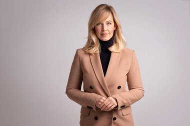 Çekici bir kadının portresi gülümseyen ve kameraya bakan. Sarı saçlı, spor ceket giyen ve izole edilmiş beyaz arka planda duran bir kadın. Uzayı kopyala Stüdyo çekimi. 