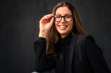 Çekici, orta yaşlı, balıkçı yaka kazak ve ceket giyen ve arka planda izole bir şekilde oturan kadın portresi. Boşluğu kopyala.