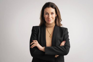 Studio portrait of an attractive woman toothy smiling and looking at camera. Brunette haired female wearing blazer and standing against isolated white background. Copy space.  clipart