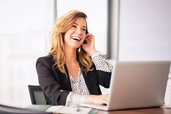 在现代化的办公室里 中年职业女性面带微笑地使用笔记本电脑 职业女性穿着夹克 — 图库照片