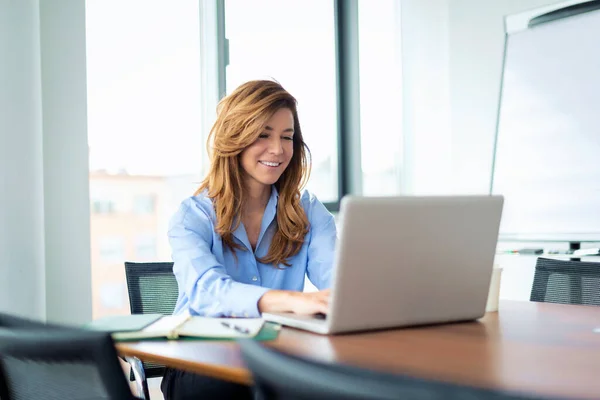 中年职业女性坐在一个现代化的办公室里 用笔记本电脑进行视频通话 穿着黑色西装的自信的女商人 — 图库照片