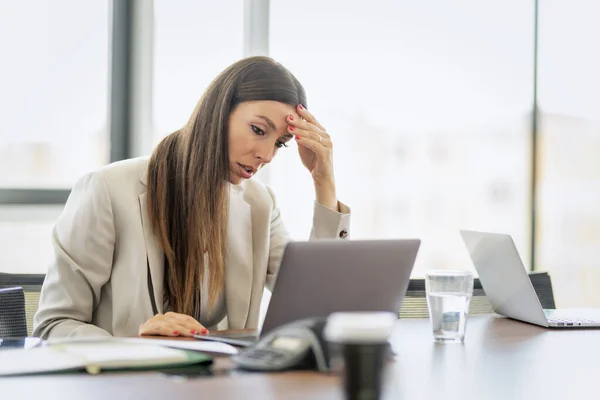 疲惫不堪的女商人 头脑清醒地坐在办公室的电脑桌前 女商人穿着夹克 工作时使用笔记本电脑 — 图库照片