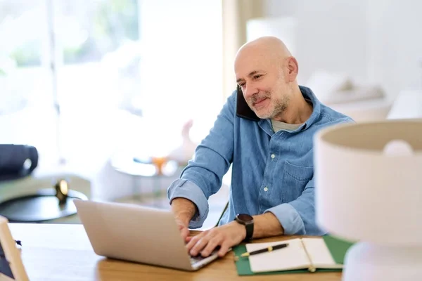 自宅でノートを使用して高齢者を自信を持って 中年の男性がオンラインで働くと机に座っている 内務省 — ストック写真