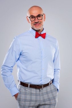 Gözlük takan, papyon takan ve ıssız bir arka bahçede duran bir adamın stüdyo portresi. Boşluğu kopyala.