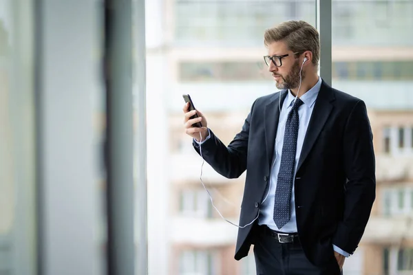 Serious Faced Businessman Using Smartphone Earphones While Standing Office Professional — Stock Photo, Image