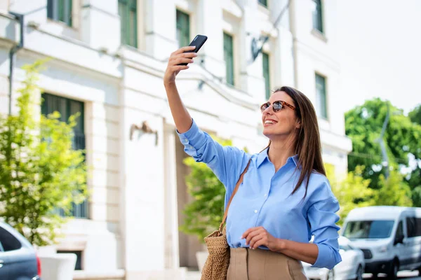 Esmer Kadın Caddede Yürüyor Akıllı Telefonuyla Selfie Çekiyor Gülen Kadın — Stok fotoğraf