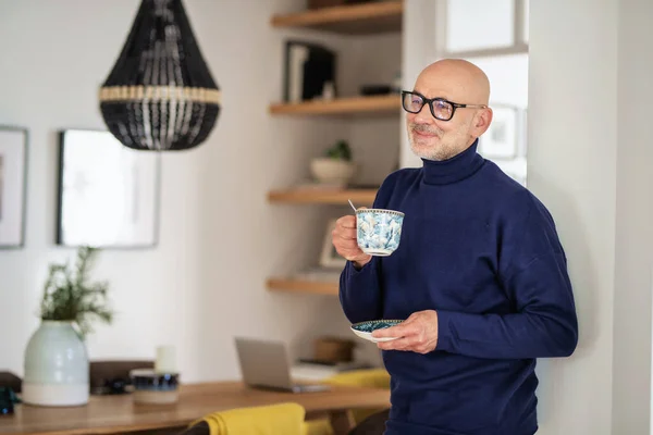 キッチンに立って お茶を飲む中年男性 タートルネックセーターと眼鏡を身に着けている自信のある男性 — ストック写真