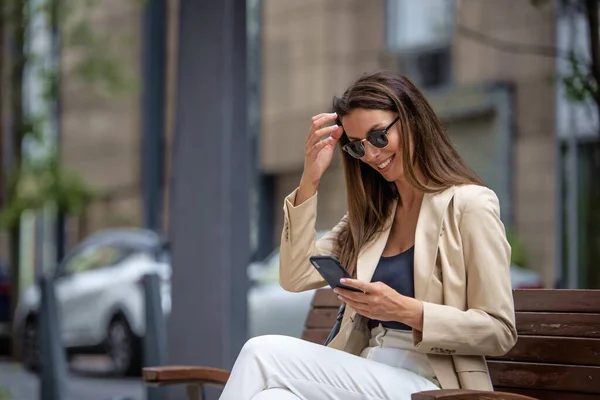 Laughing Brunette Haired Woman Sitting Bench Street Using Phone Attractive — Stock Photo, Image