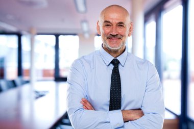 Ofisteki kendinden emin iş adamının portresi. Orta yaşlı profesyonel bir adam kameraya bakıyor ve gülümsüyor. Boşluğu kopyala. 