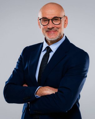 Gri arka planda duran orta yaşlı bir iş adamının portresi. Takım elbiseli ve gözlüklü kendine güvenen profesyonel bir adam. Boşluğu kopyala.