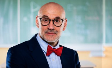 Orta yaşlı matematik profesörü sınıfta karatahtanın önünde duruyor..