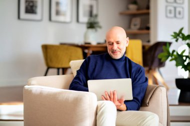 Evde defter kullanan kendinden emin kıdemli bir adam. Orta yaşlı bir erkek çevrimiçi çalışıyor ya da video konferansı yapıyor. Merkez Ofis.