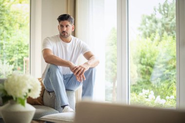 Sıradan kıyafetler giyen ve evdeki kanepede dinlenen bir adamın portresi. Düşüncelere dalmış orta yaşlı bir adam..