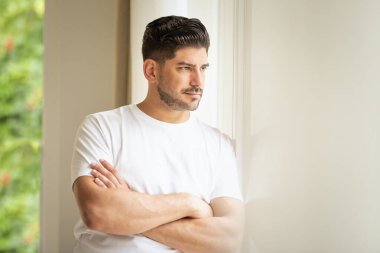 Düşünen bir adamın, kollarını pencerede kavuşturup dışarı bakarken görüntüsü.. 