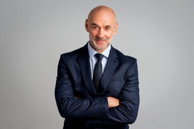 İzole edilmiş arka planda duran orta yaşlı iş adamı. Takım elbiseli, kravatlı ve kameraya bakan kendine güvenen bir adam. Boşluğu kopyala.
