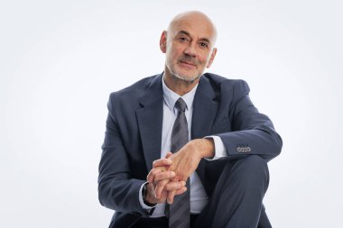 Orta yaşlı iş adamı takım elbise ve kravat takıyor ve izole edilmiş beyaz arka planda oturuyor. Boşluğu kopyala. 