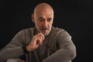 Siyah arka planda orta yaşlı bir adamın stüdyo resmi. Kel ve sakallı bir adam izole edilmiş arka planda günlük kıyafetler giyiyor. Derin düşüncelere. Boşluğu kopyala. 