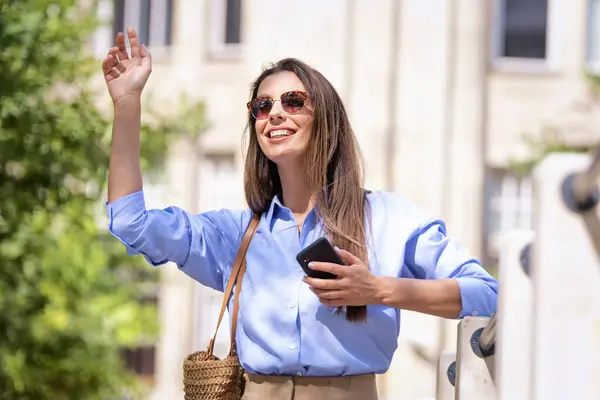 Çekici Bir Kadın Sokakta Yürürken Elinde Akıllı Bir Telefonla Taksi — Stok fotoğraf