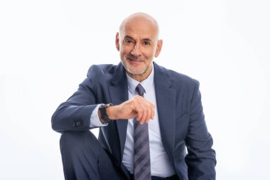 Orta yaşlı işadamı takım elbise giyip izole edilmiş arka planda kravat takıyor. Beyaz arka planda oturan kendine güvenen bir adam. Boşluğu kopyala.