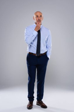 Gri arka planda duran tam uzunlukta bir iş adamı. O, gömlek ve kravat takıyor. Boşluğu kopyala.