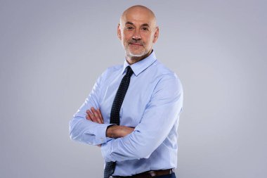 Gri arka planda duran gülümseyen iş adamının görüntüsü. O, gömlek ve kravat takıyor. Boşluğu kopyala.