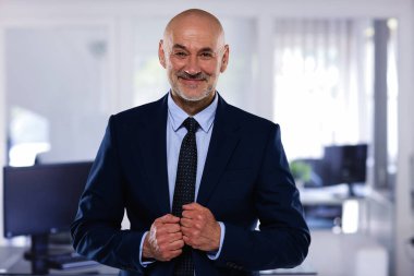 Ofiste duran orta yaşlı bir iş adamının portresi. Takım elbiseli ve kravatlı profesyonel bir adam..