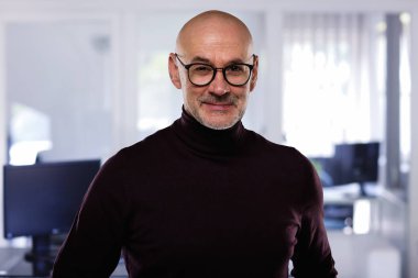 Ofiste duran yakışıklı sıradan bir iş adamı. Balıkçı yaka kazak ve gözlük takan kel adam.. 