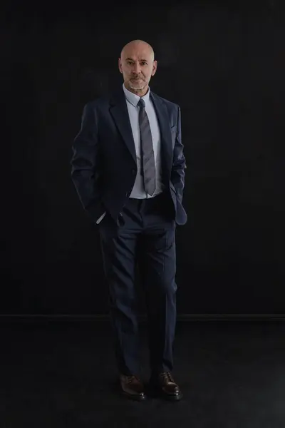 Full length of mid agd man wearing suit and standing against isolated black background. Copy space.