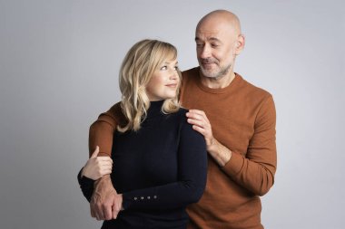 Soyutlanmış bir geçmişe sahip orta yaşlı bir çift birbirlerine bakıyor. Sarışın bir kadın ve günlük kıyafetler giyen orta yaşlı bir adam. Yakışıklı bir adam ortağına sarılıyor. Boşluğu kopyala.