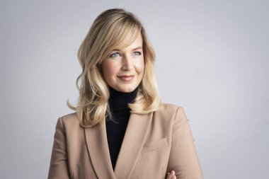 İzole edilmiş beyaz arka planda duran çekici sarı saçlı kadın. Siyah kazak ve ceket giyen olgun bir kadın. Boşluğu kopyala.