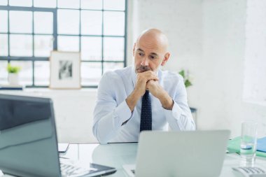 Ofiste oturan orta yaşlı bir iş adamı ve dizüstü bilgisayar kullanıyor. Erkek girişimci bilgisayarında telekonferans toplantısı yapıyor..