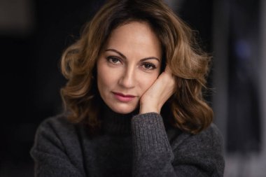 Çekici, olgun bir kadının düşünceli bakışları. Sarı saçlı, gri kazaklı bir kadın.. 