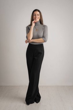 Çekici, orta yaşlı bir kadın balıkçı yaka kazak ve siyah pantolon giyiyor. Boşluğu kopyala. 