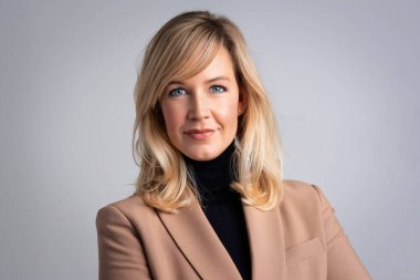 Ceket giyen ve izole edilmiş arka planda duran sarışın bir kadının stüdyo portresi. Boşluğu kopyala.