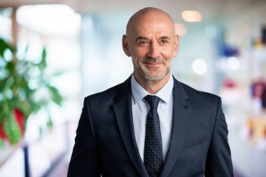 Orta yaşlı iş adamı takım elbise ve kravat takıyor ve ofis lobisinde dikiliyor. Boşluğu kopyala.