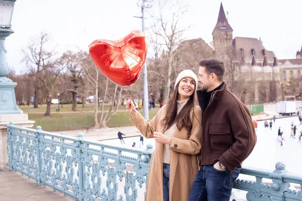 在城市里站在一起的夫妻他们手里拿着心形的气球 庆祝情人节 快乐的女人和英俊的男人庆祝他们的爱情 — 图库照片