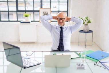 Ofisinde çalışan orta yaşlı mutlu bir işadamının portresi. Dizüstü bilgisayar kullanan ve video görüşmesi yapan profesyonel bir adam.. 