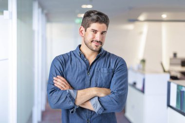 Ofiste kollarını kavuşturmuş yakışıklı bir iş adamı. Kameraya bakıyor ve gülümsüyor. Gündelik kıyafetler giyen kendinden emin bir erkek. Merkez Ofis. 