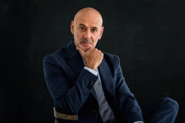 Siyah arka planda bir stüdyo resmi düşünüyorum. Tecrit edilmiş arka planda takım elbiseli kel ve sakallı bir adam. Boşluğu kopyala. 