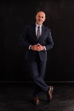 Siyah arka planda orta yaşlı bir adamın stüdyo resmi. Tecrit edilmiş arka planda takım elbiseli kel ve sakallı bir adam. Tam yol ileri. Boşluğu kopyala. 